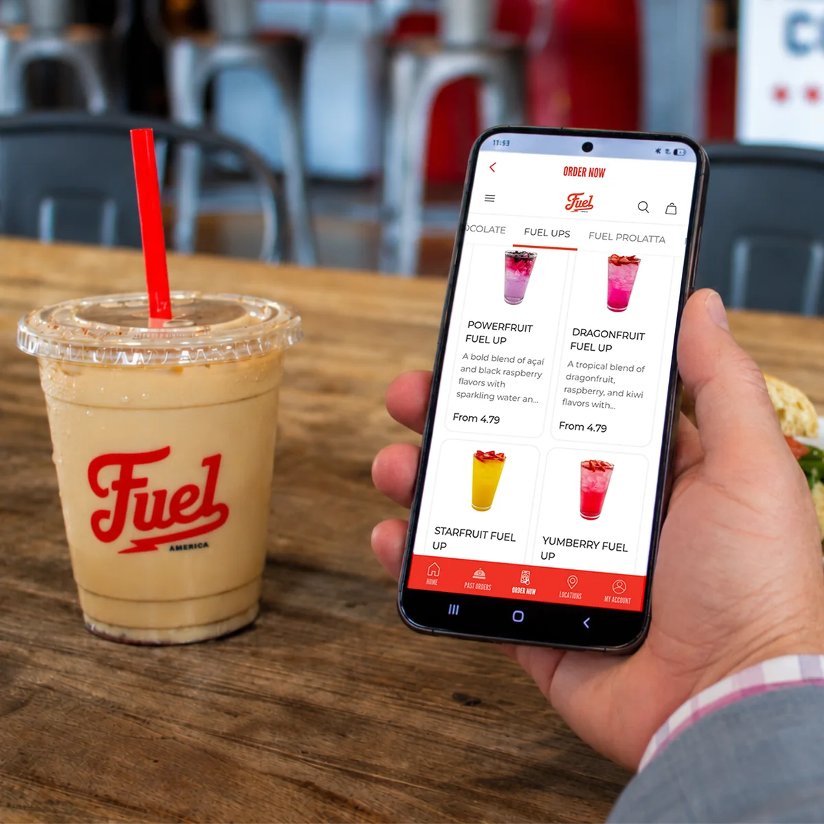 Fuel America app on a smartphone beside an iced coffee