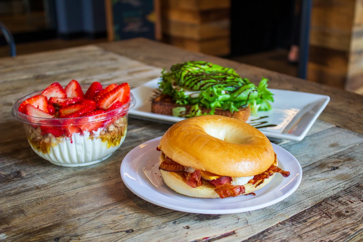 A breakfast sandwich, avocado toast, and yogurt with strawberries.