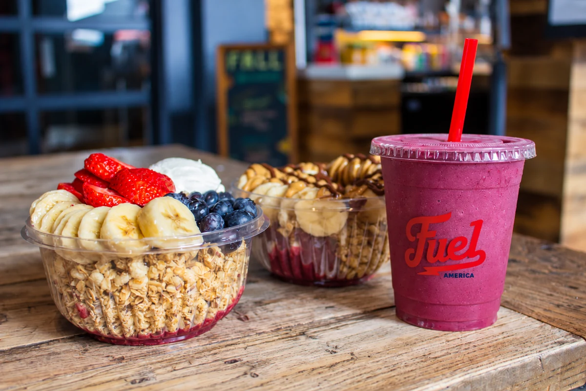 Fruit-topped bowls beside a berry smoothie at Fuel America.