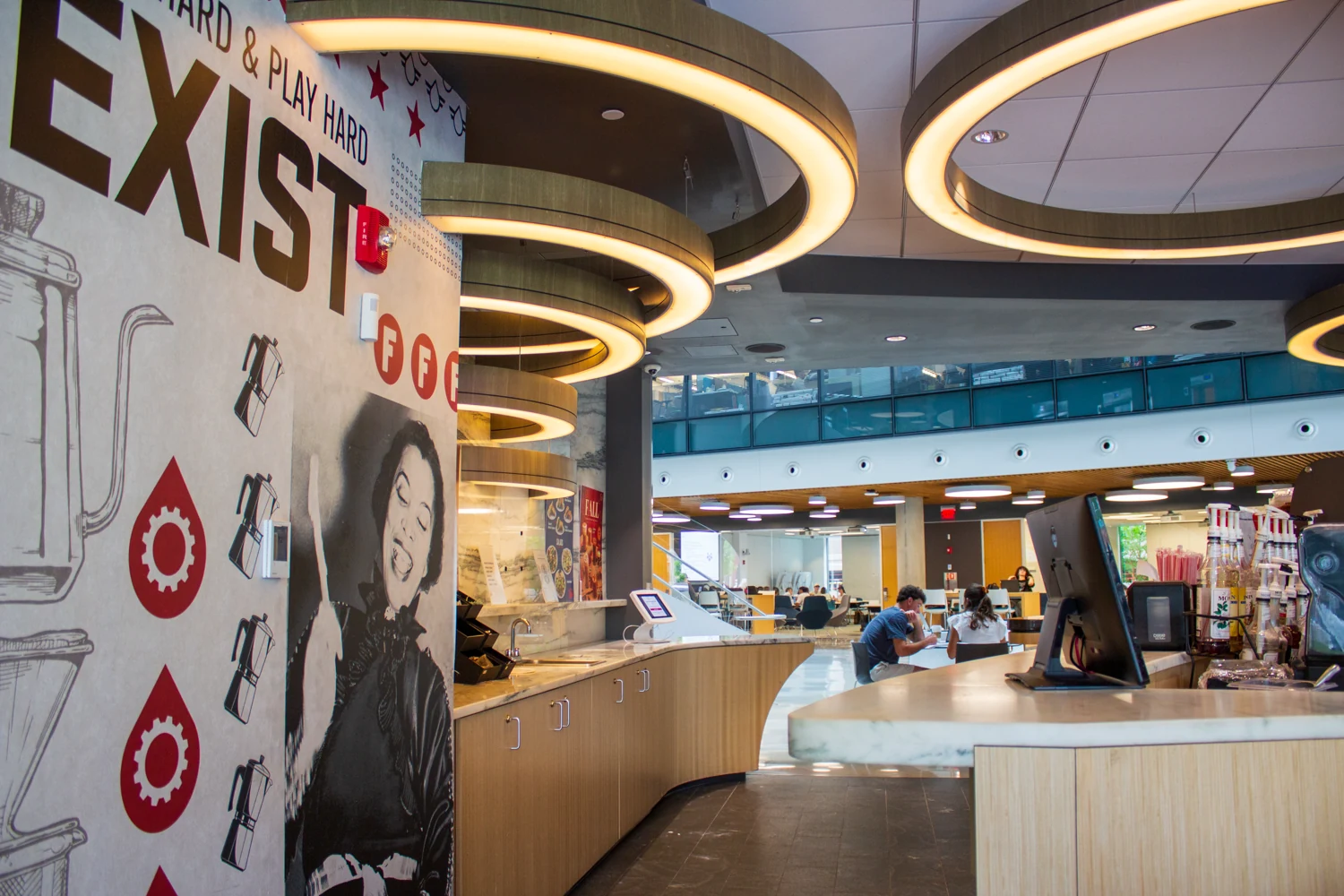 Curved coffee counter and mural beneath ring lights at Fuel America Northeastern