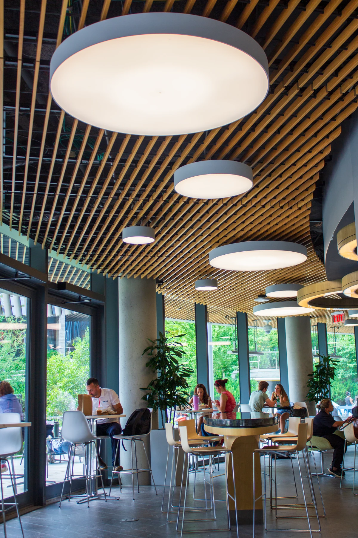 Guests at café tables beside the tall windows at Fuel America Northeastern