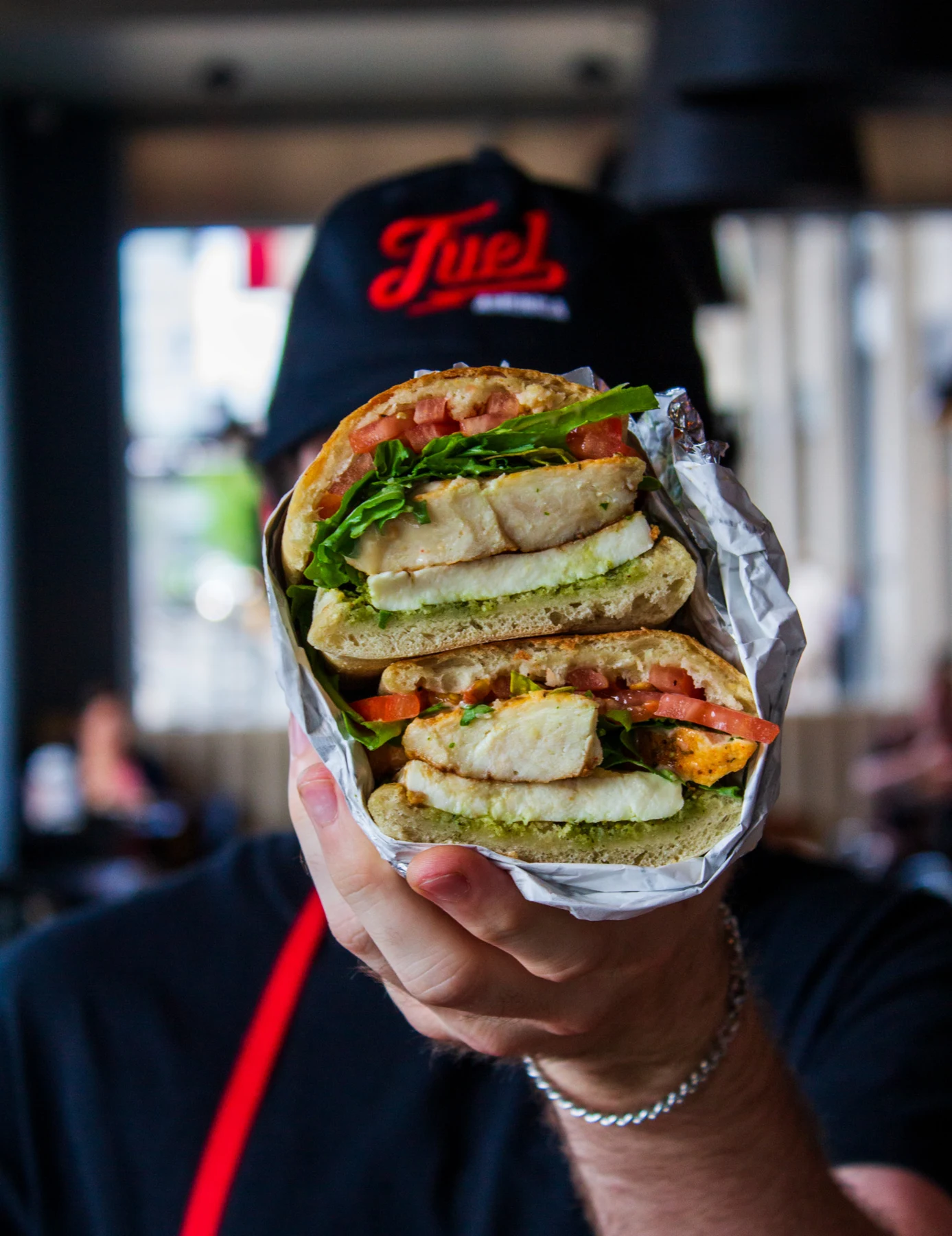 A Fuel America team member holding a freshly prepared sandwich