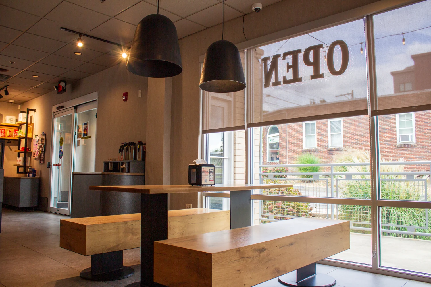 Wooden tables and bench seating beside the windows at Fuel America Weymouth